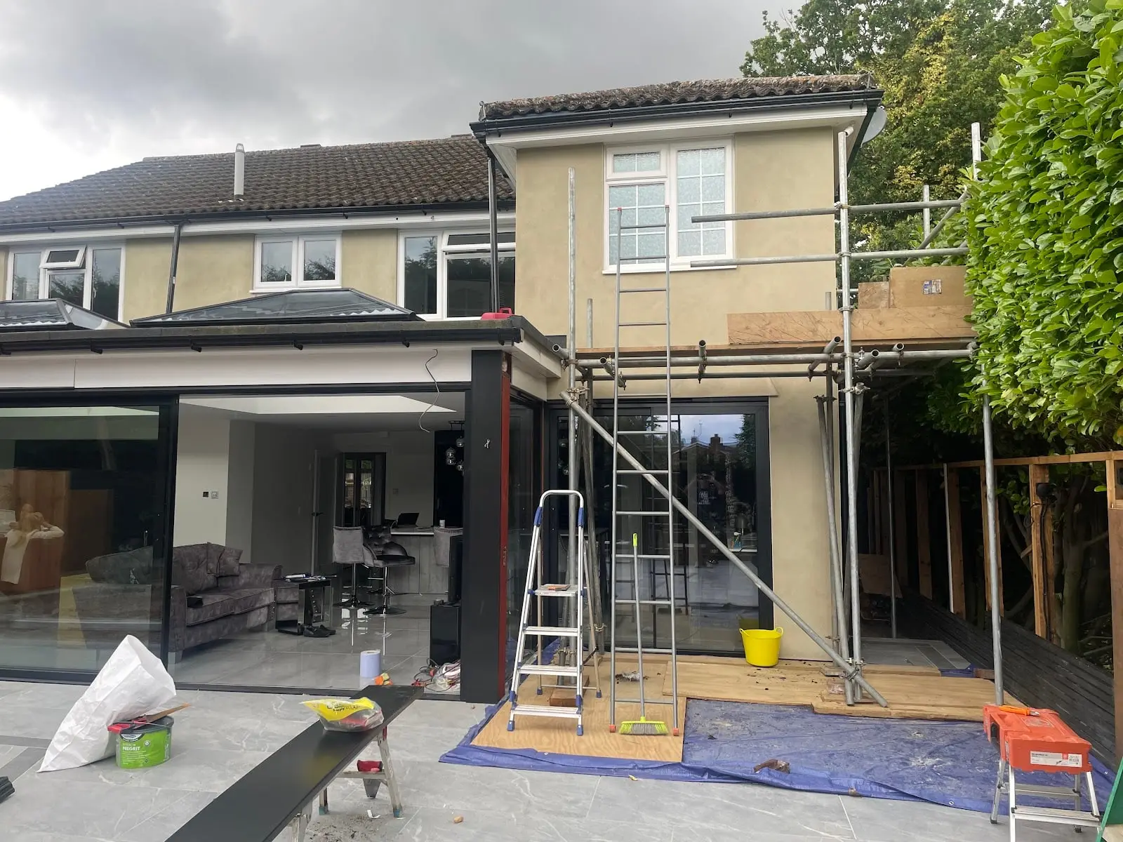 The two-storey side addition rendered to match the house, with the scaffold still standing