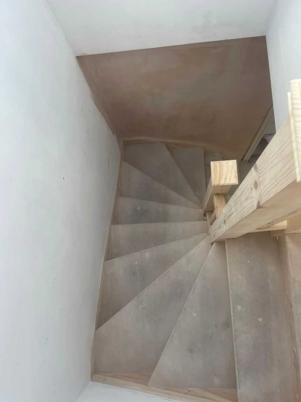 Unfinished timber winder stairs rising into a converted loft